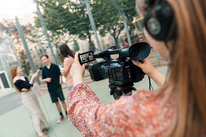 mz2025 x ste.krenn-187 Einer Jugendlichen mit langen Haaren mit Kamera in der Hand über die Schulter geschaut. Gefilmt wird eine Interview-Szene